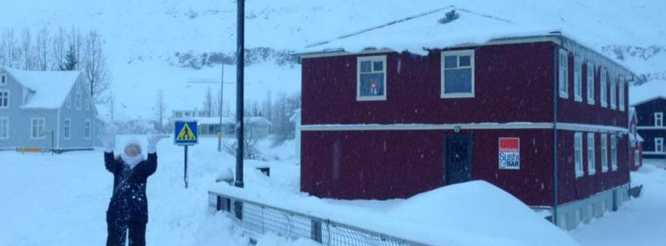 woman standing in snow next to a house in Iceland