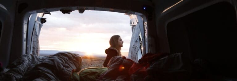 Sleepingbags inside camper woman standing outside