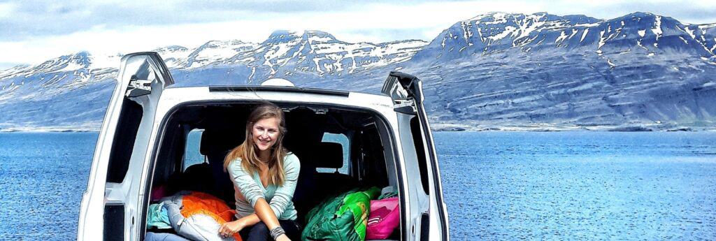 woman sitting inside a rent.is campervan with luggage