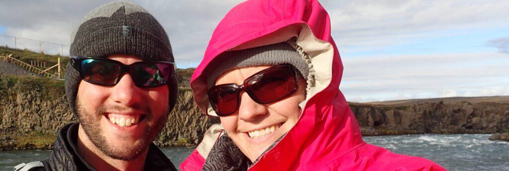 couple with sunglasses smiling by a lake
