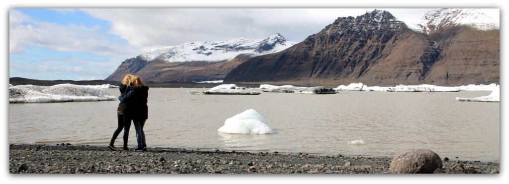 two women hugging in front of lake and mountains