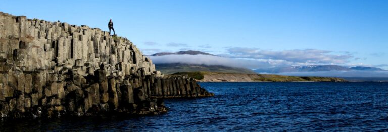person standing on basalt rock coastline