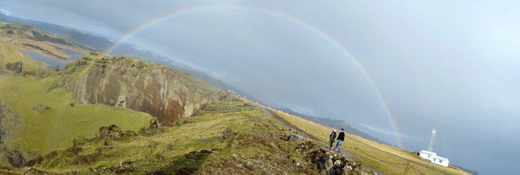 people undar a rainbow in the icelandic nature