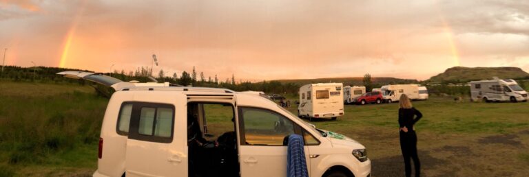 camper van at a campsite with rainbow in background