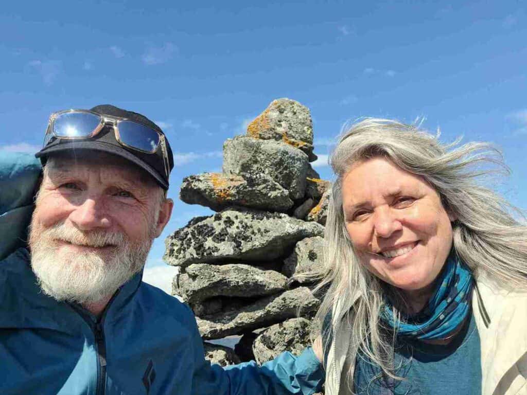 A couple posing next to a rock stack.