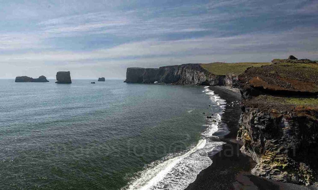 A black beach view, ocean waves falling by it.