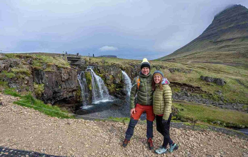 A couple posing next to a small waterfall.