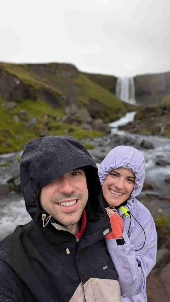 A couple stands by a small waterfall and river in Iceland