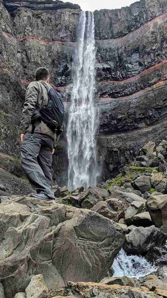 A man looking up at a waterfall, Iceland exploration