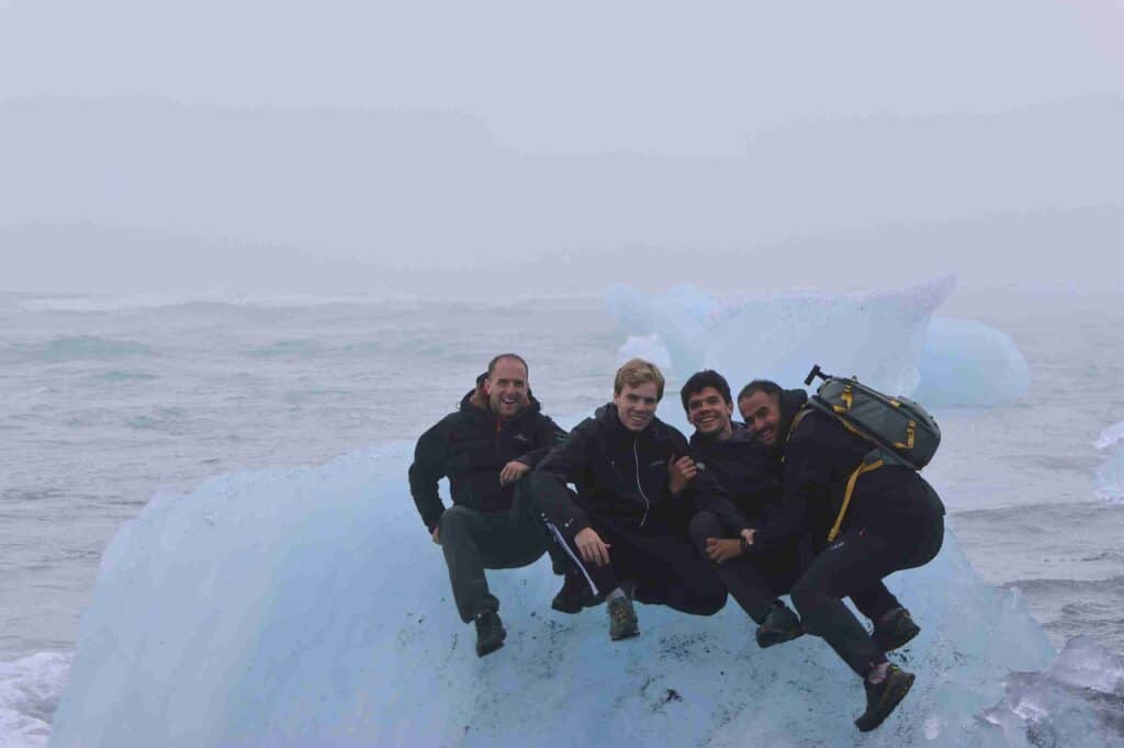 Four guys sitting on a large piece of Ice.