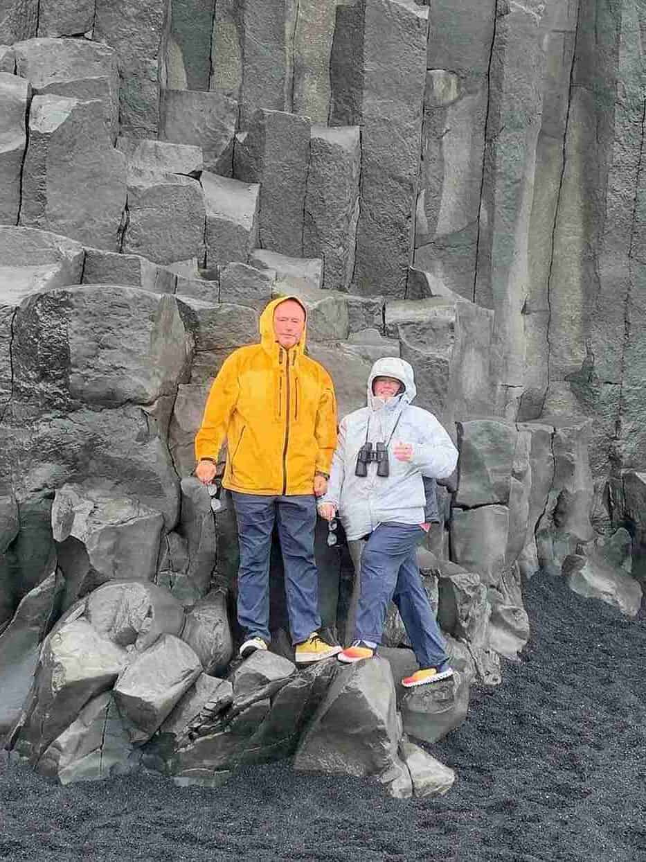 A couple standing by a rock wall on the black beach