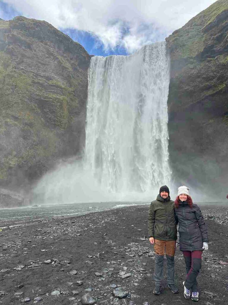 A couple stands by the Skógarfoss Waterfall