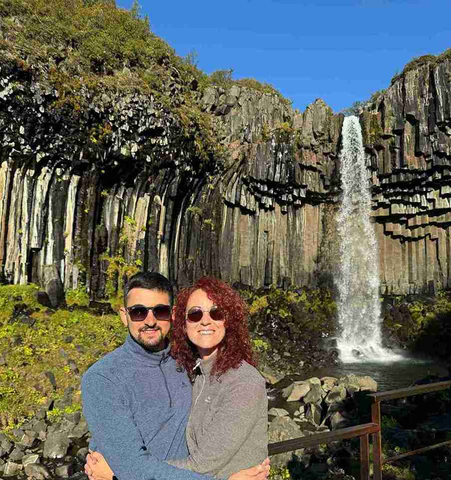 A couple stands by a small waterfall 