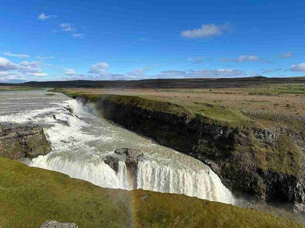 A large waterfall, looking overhead. A small rainbow appears.